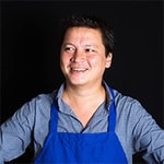 Kenji Lopez-Alt in a black background with chef suit, guest of the re run of previous episode about food, home and connections with Dan Pashman