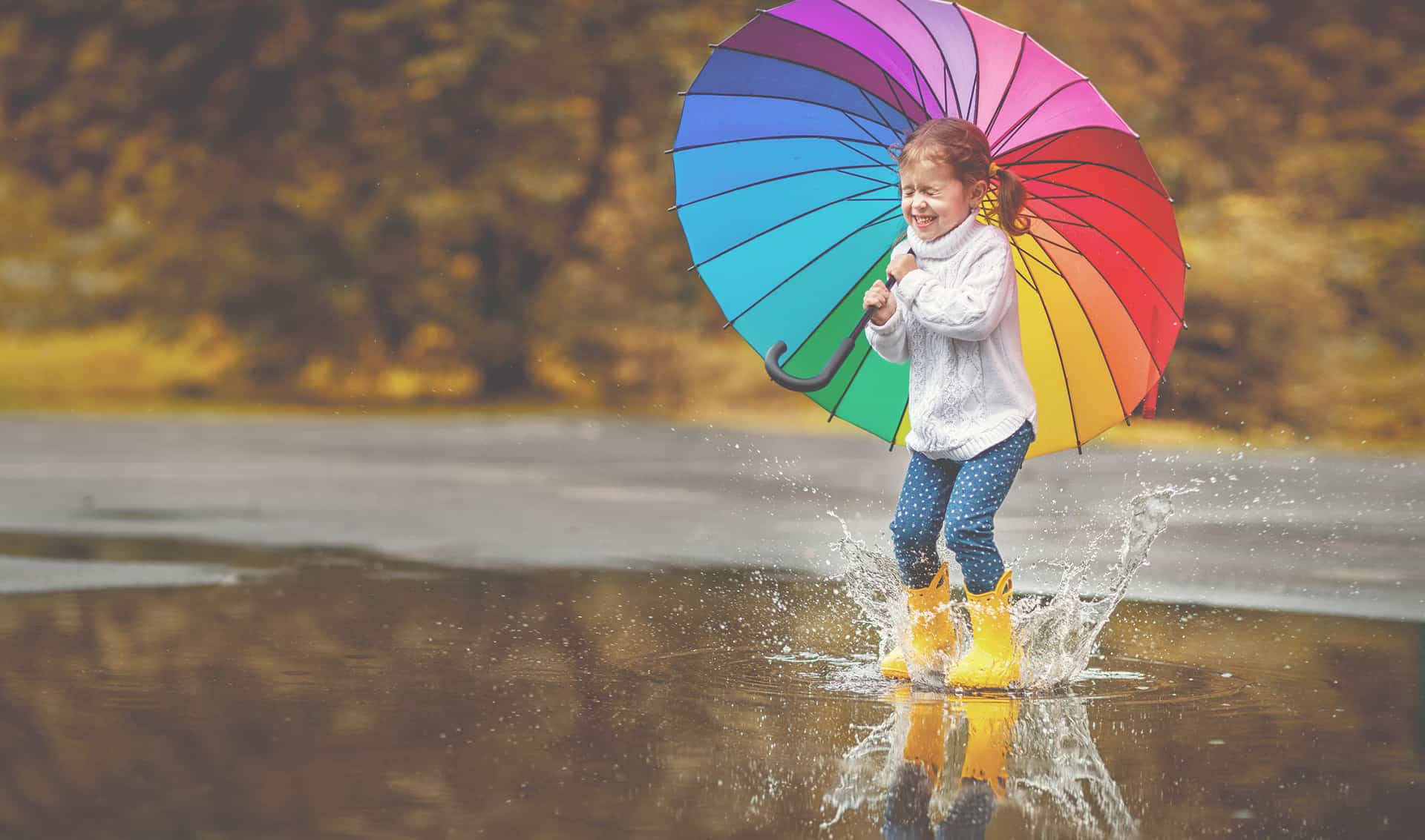 Children playing with a colorful umbrella in a lake referring to health & wellness, category from positive psychology podcast Harvesting Happiness with Lisa Cypers Kamen.