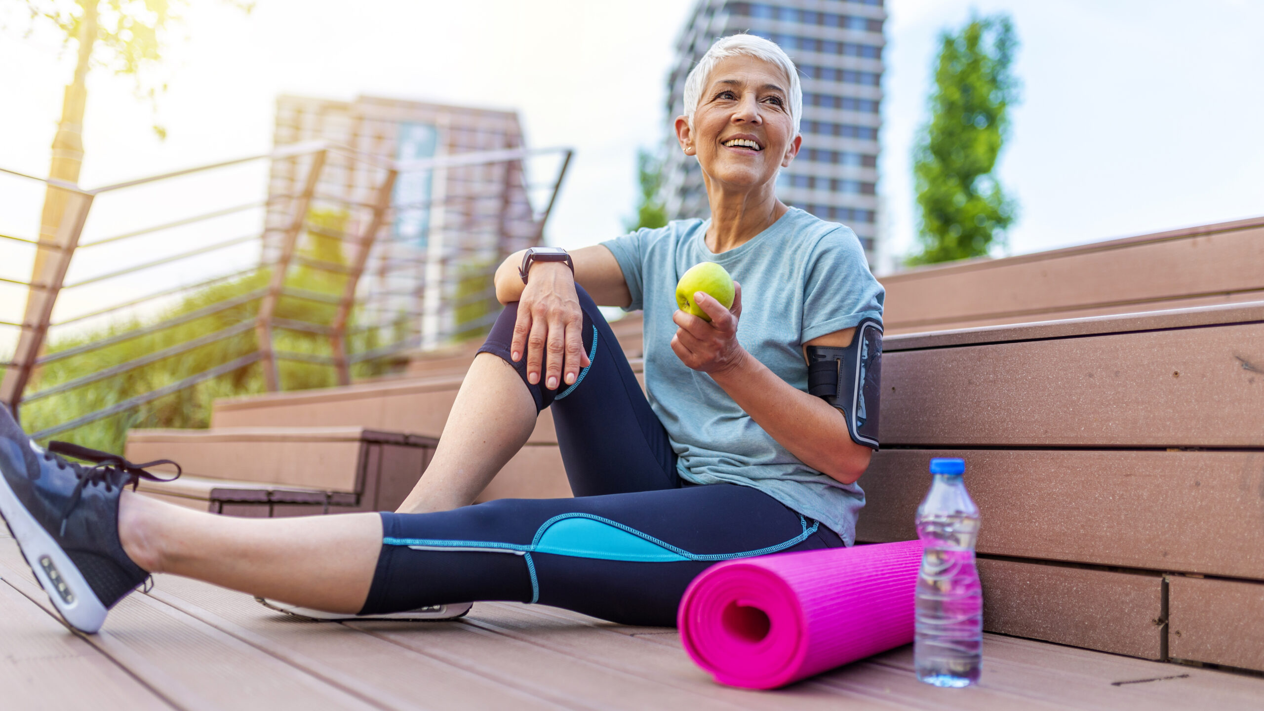 Woman with gray hair exercising in the city while eating an apple, image of new podcast episode about hardwired brains wtih Dr. Robert Lustig & Dr. Robert Barrett
